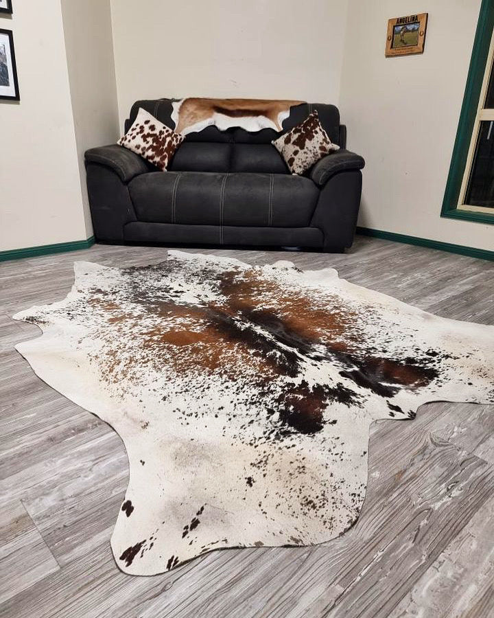 Salt and pepper cowhide rug in front of a black leather lounge